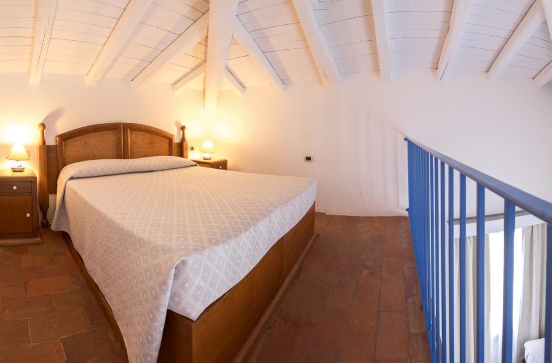 Camera da letto mansardata con letto matrimoniale e luci soffuse.
