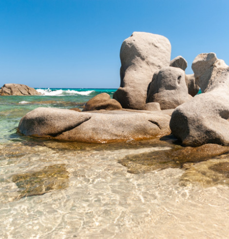 Costa rocciosa con faraglioni nel mare e vegetazione lussureggiante.